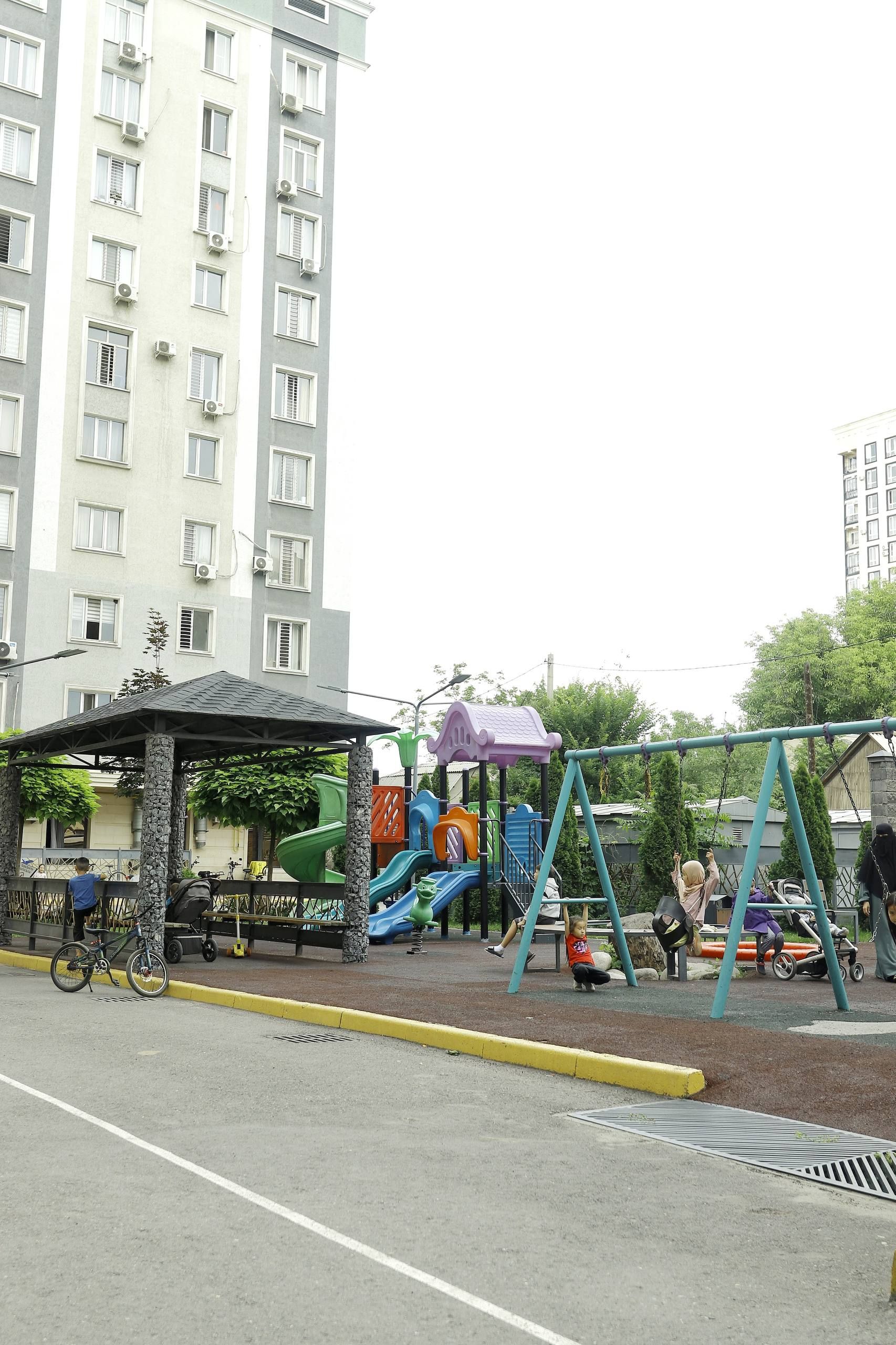 A playground with slides and swings, a covered seating area, and a bicycle parked nearby.