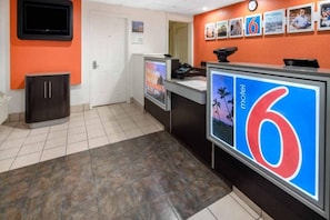 A reception area with a counter, a clock, and a series of framed pictures on the wall. - 2 Full Beds | Micfridge (Ventura)