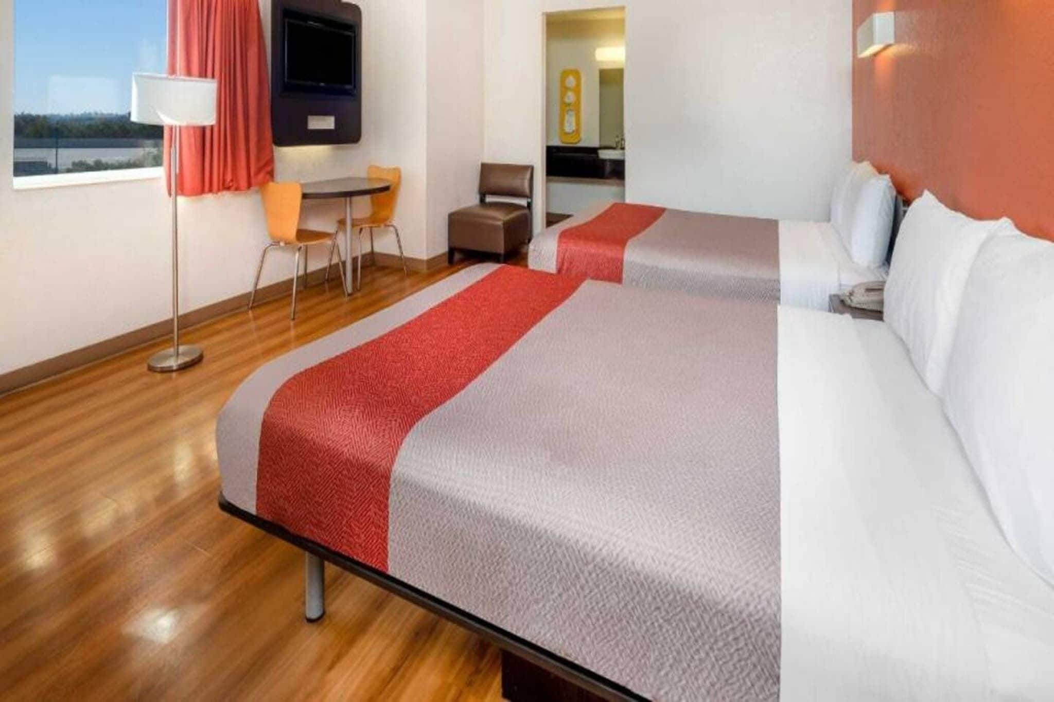 Een hotelkamer met twee bedden, een bureau, een stoel, een televisie en een raam met uitzicht.