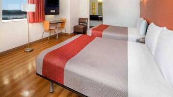 Een hotelkamer met twee bedden, een bureau, een stoel, een televisie en een raam met uitzicht.