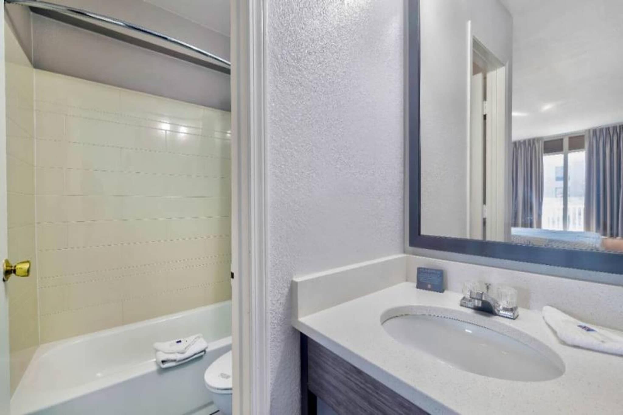 A bathroom with a bathtub, a sink, and a mirror.