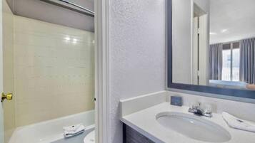 A bathroom with a bathtub, a sink, and a mirror.