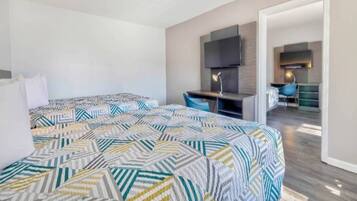 A hotel room with a bed, a desk, and a TV.