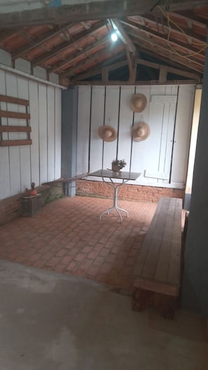 A room with a brick floor, a wooden table, and a hanging light fixture. - Beautiful country house for weekend getaways with the family. Safe and peaceful location. (Bragança Paulista)