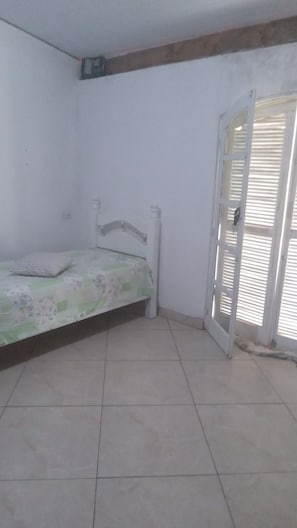 A room with a bed, a door, and a tiled floor. - Beautiful country house for weekend getaways with the family. Safe and peaceful location. (Bragança Paulista)