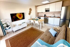 A modern living room with a sofa, a coffee table, and a dining area with a table and chairs. - Delightful 2-bedroom oceanview apartment with AC in Quarteira (Quarteira)