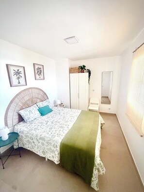 Une chambre à coucher comprenant un lit, une table de chevet, une lampe, une armoire et un miroir.