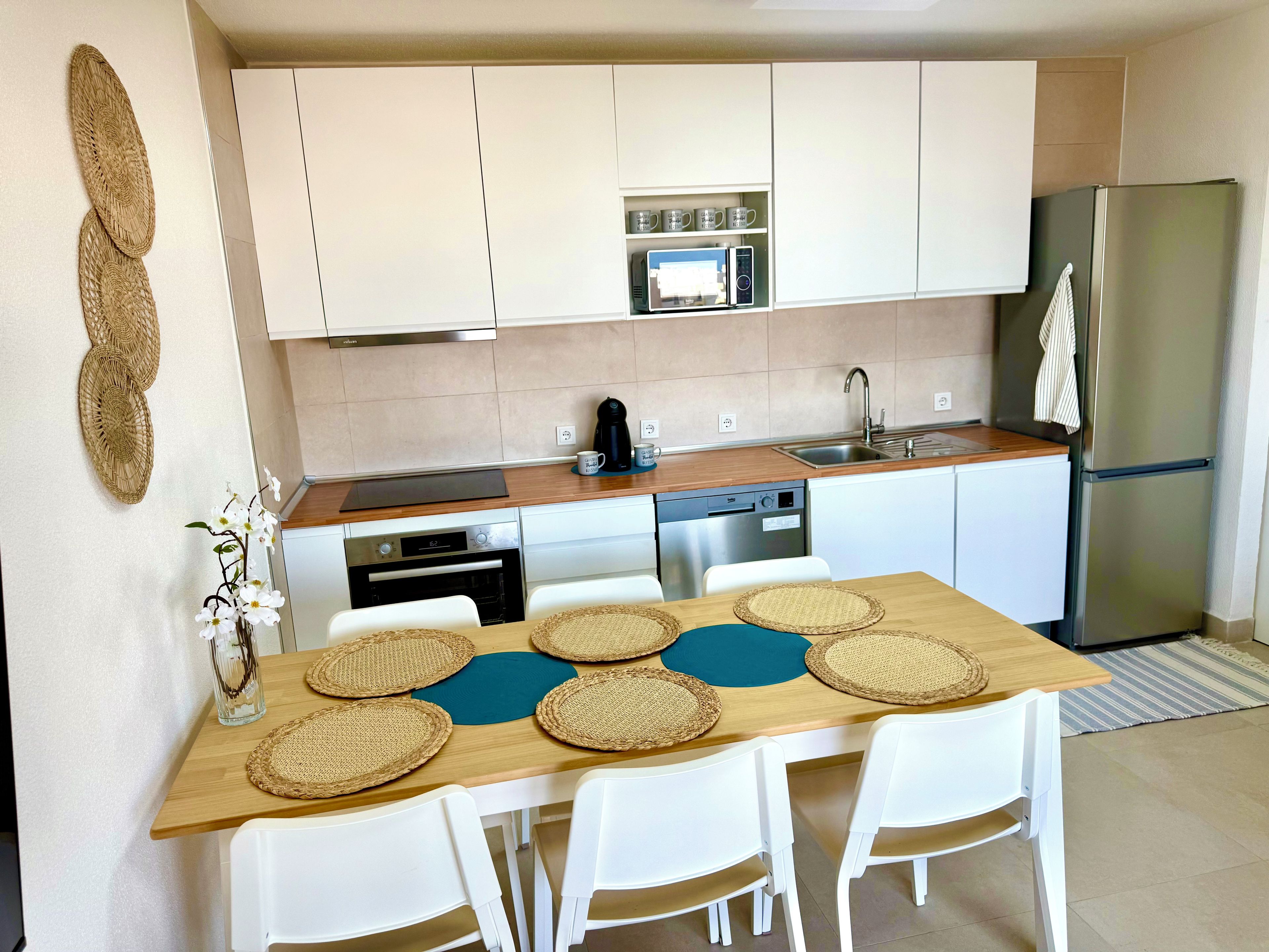 A modern kitchen with white cabinets, a stainless steel refrigerator, a microwave, and a dishwasher.