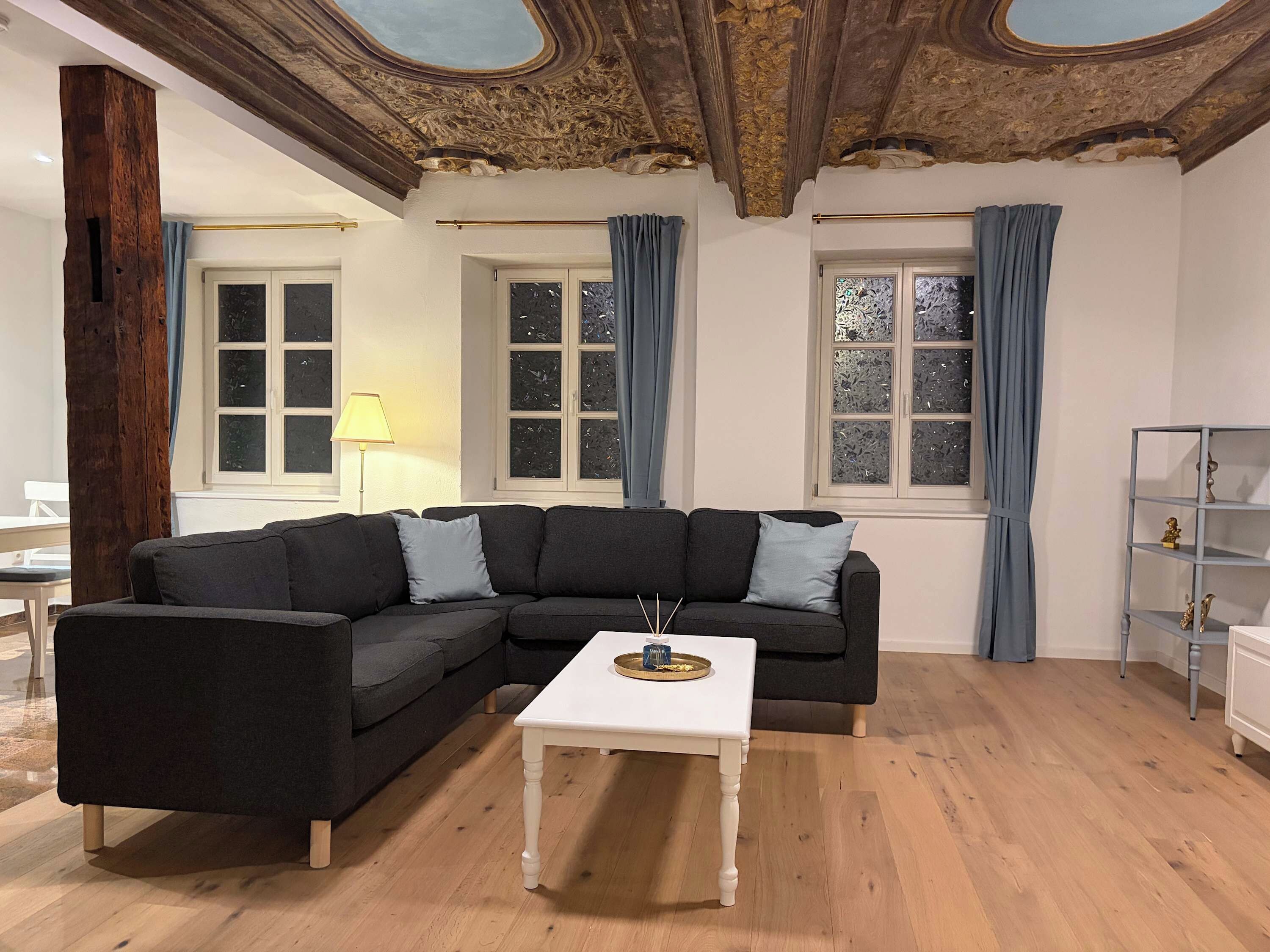 Ein Wohnzimmer mit einem dunkelgrauen Ecksofa, einem weißen Couchtisch und Holzboden.
