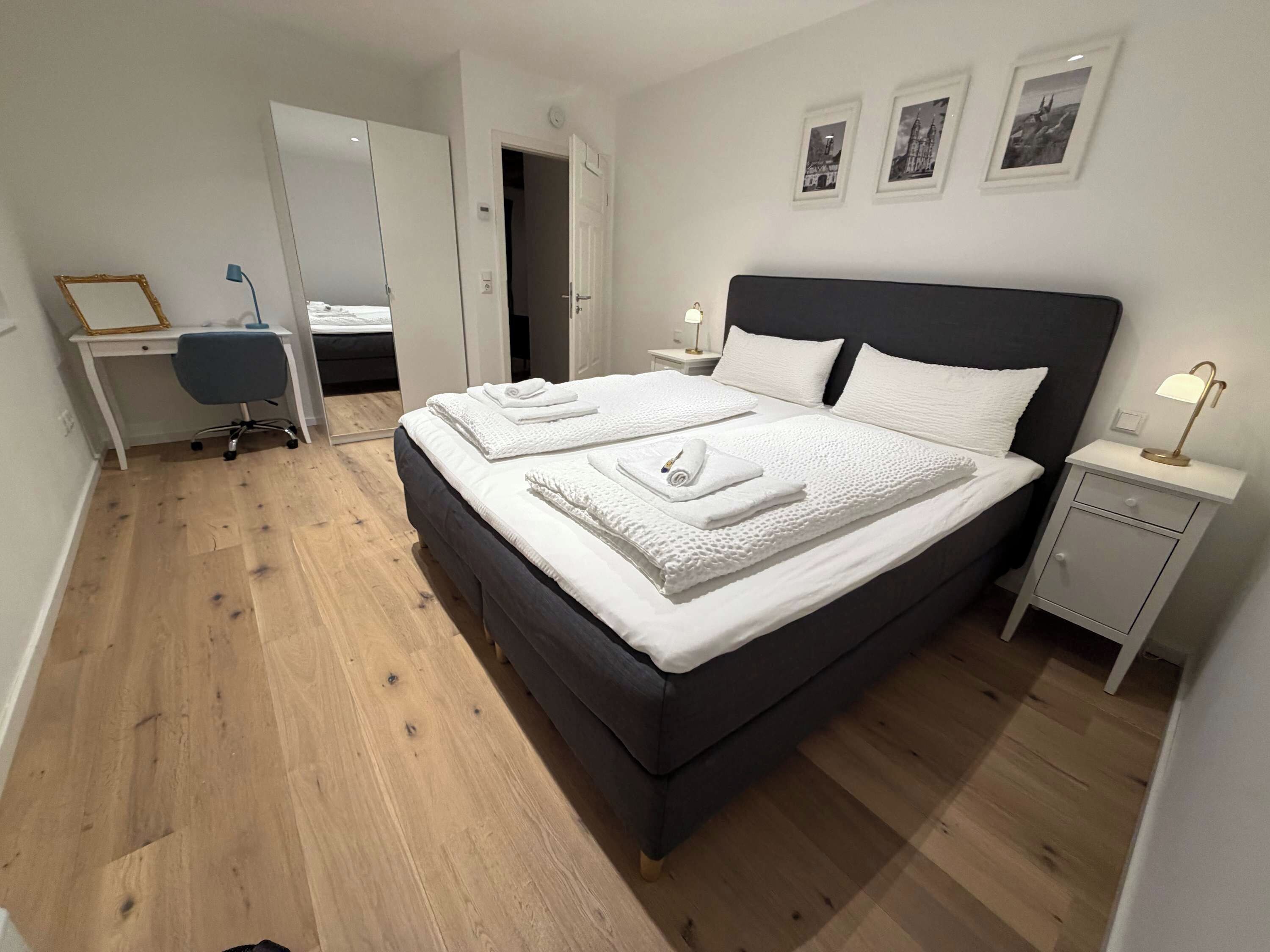 Un dormitorio con una cama grande, mesitas de noche, un escritorio y una silla.