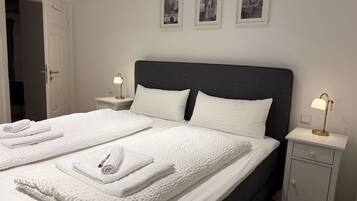 Ein Hotelzimmer mit einem Doppelbett, zwei Nachttischen, einem Beistelltisch und drei gerahmten Bildern an der Wand.