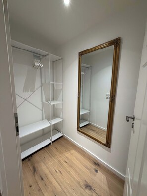 Un dressing accessible sans porte, doté d’étagères ouvertes et d’un grand miroir sur toute la hauteur.