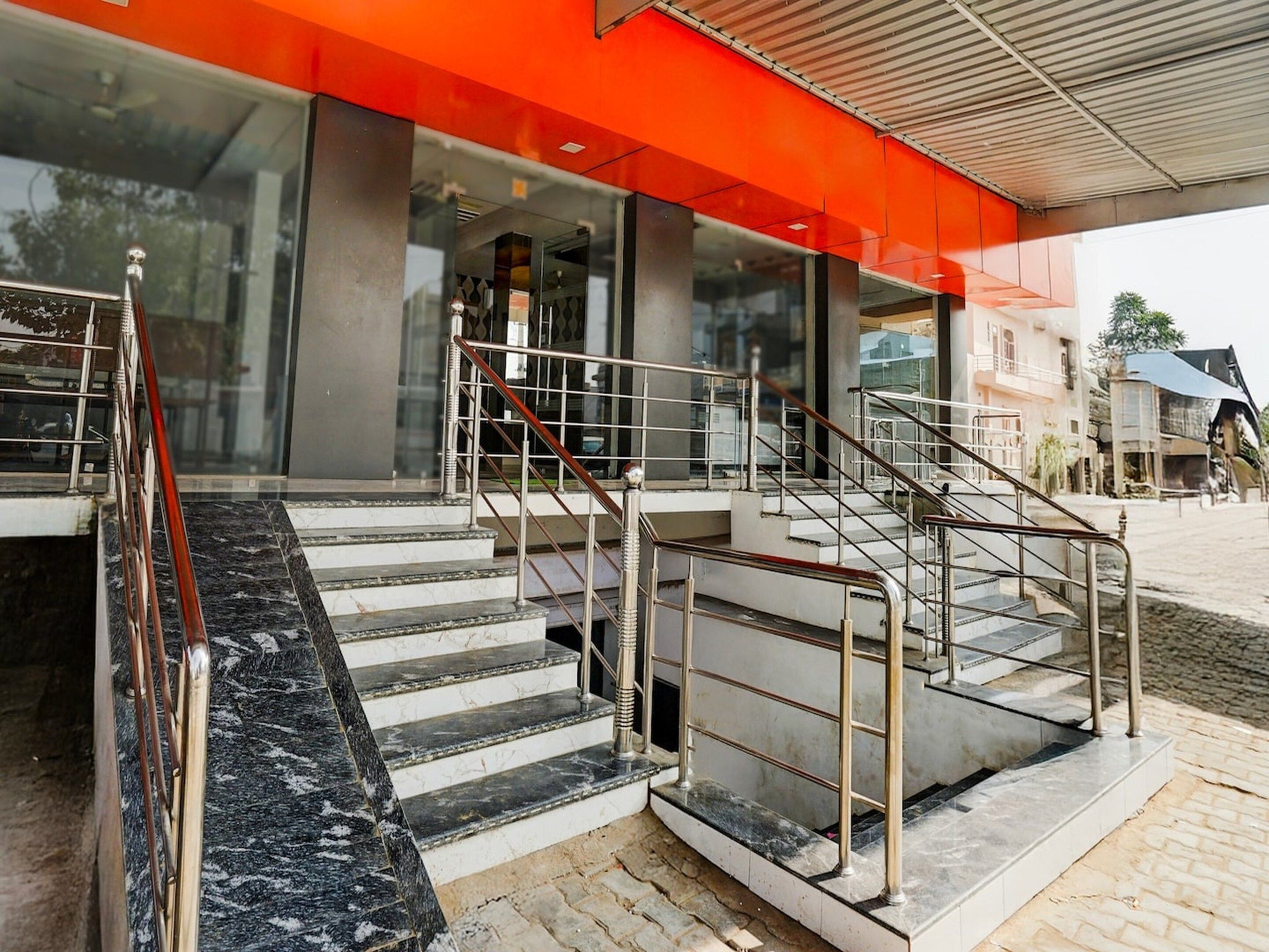 A staircase leading to a building with a red awning and a glass entrance.