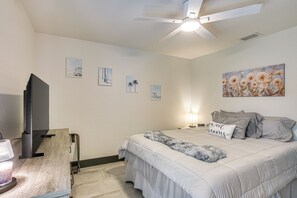 A bedroom with a bed, a ceiling fan, a television, and artwork on the wall. - Outdoor Oasis! Luxe Waterfront Gem in Lehigh Acres (Lehigh Acres)