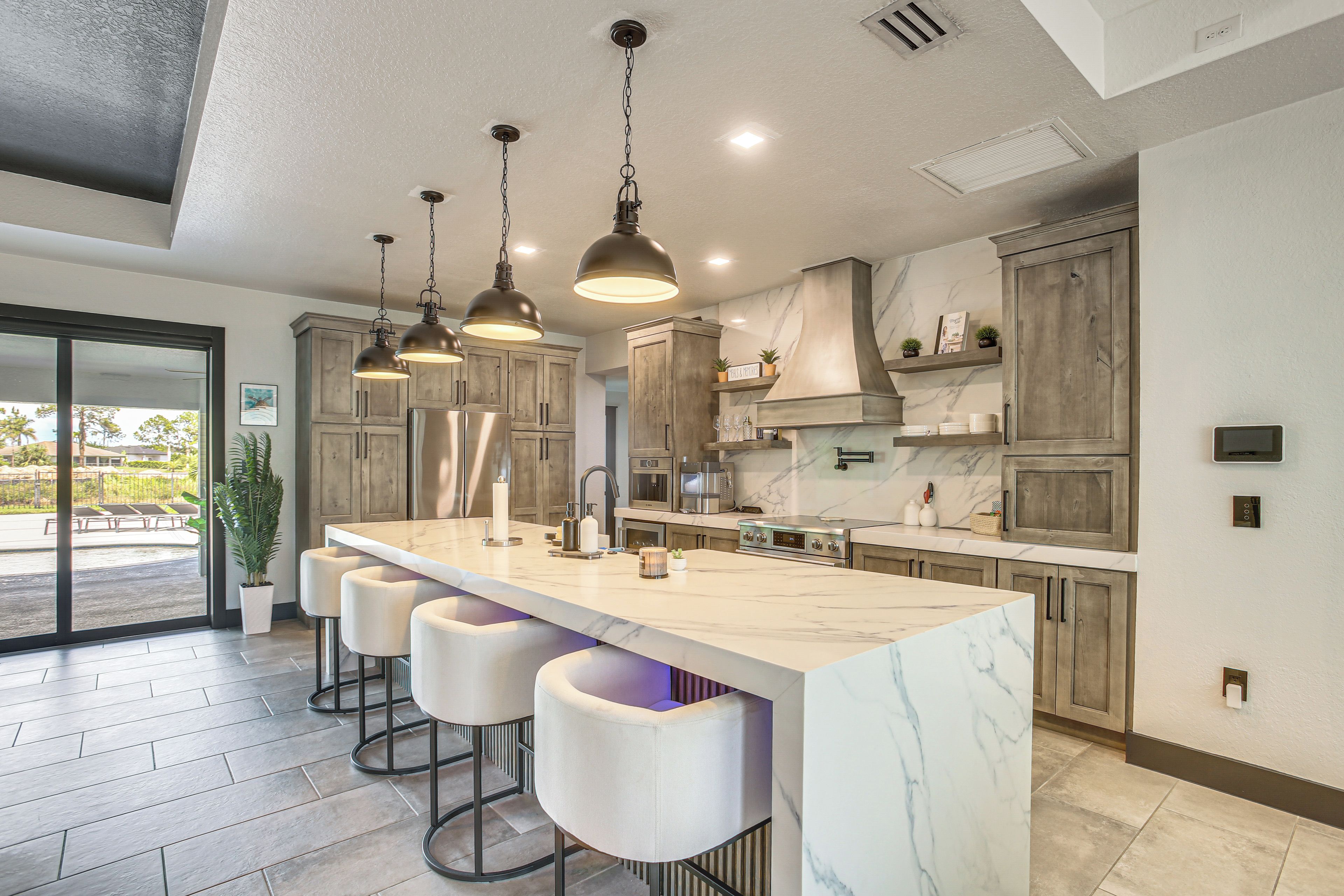 Una cocina moderna con encimera de mármol, iluminación colgante y taburetes de bar.
