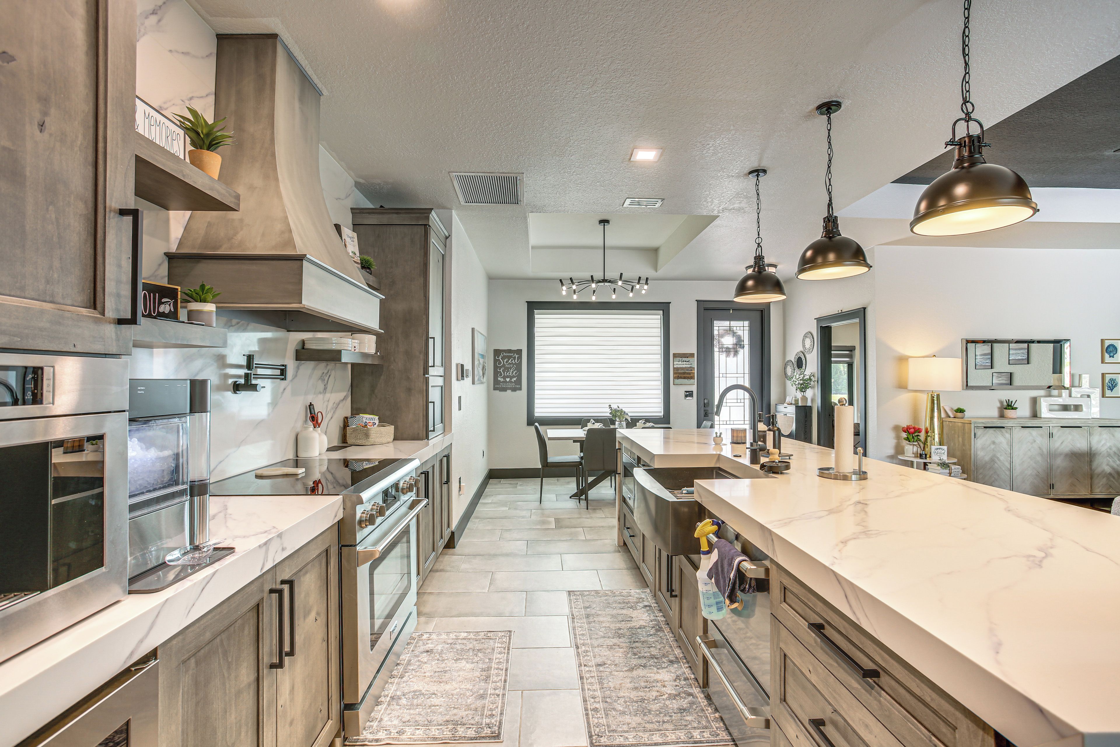 Una cocina moderna con una isla central, electrodomésticos de acero inoxidable e iluminación colgante.
