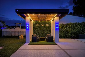 Een overdekt terras met een groene wand en lichtslingers.