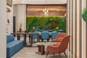 Un área de descanso moderna con una pared verde, asientos azules y una mesa redonda.