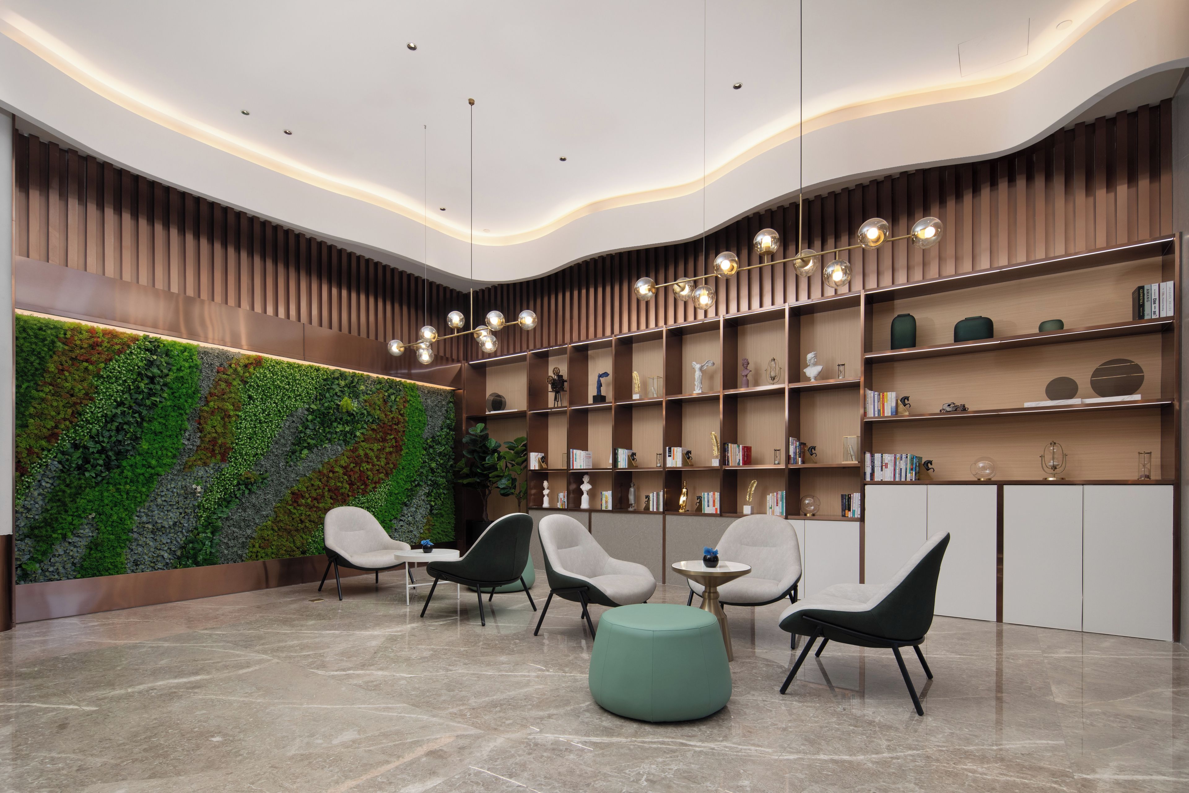 A modern reception area with a curved wall, a green vertical garden, and a collection of bookshelves.