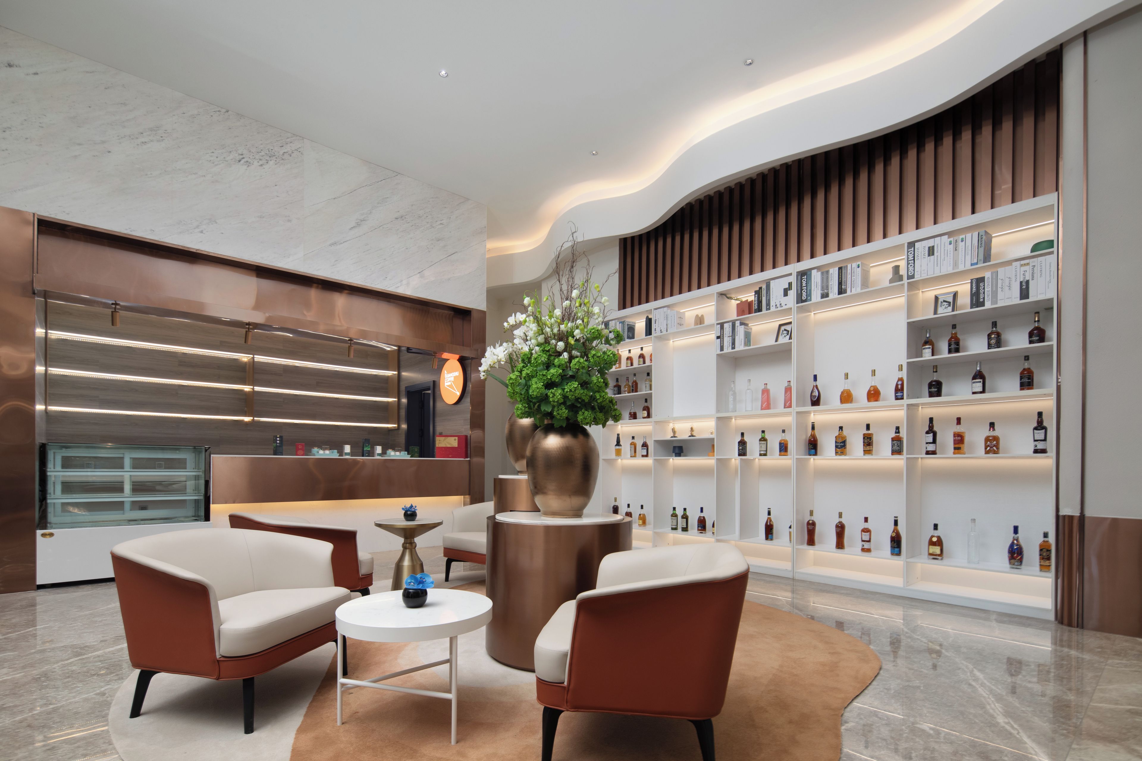 A modern lobby with a reception desk, seating area, and a wall of liquor bottles.