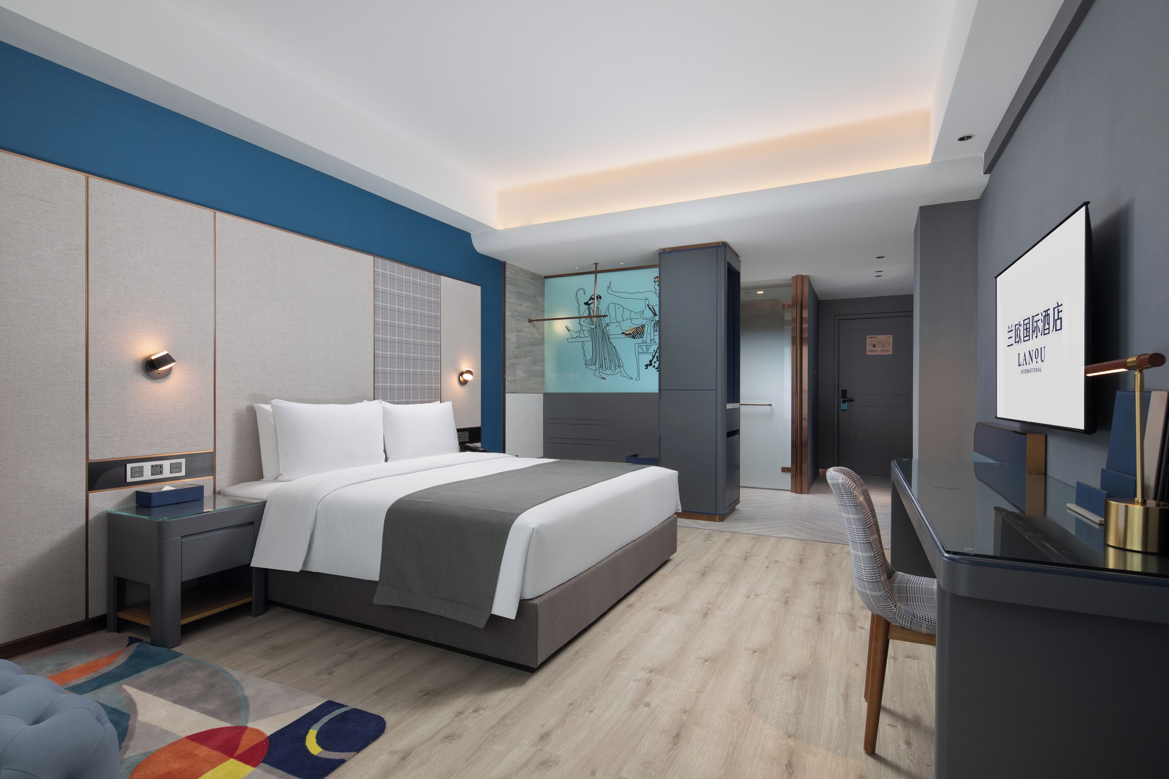 A modern hotel room with a large bed, bedside tables, a desk, and a television.