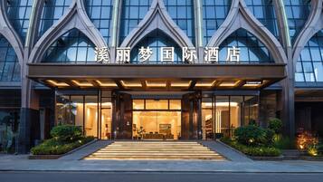 A hotel entrance with a modern design, featuring a glass facade and a prominent entrance with steps leading up to it.