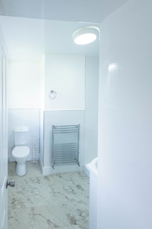 A bathroom with a toilet, a towel rack, a radiator, and a marble floor. - The Stanley Arms Hotel by Guestz (Seascale)