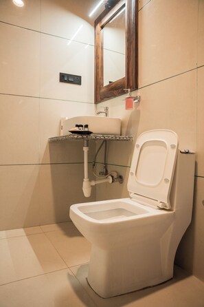 A bathroom with a toilet, sink, and mirror. - HOTEL ROYAL LAKHINA JAISALMER (Jaisalmer)
