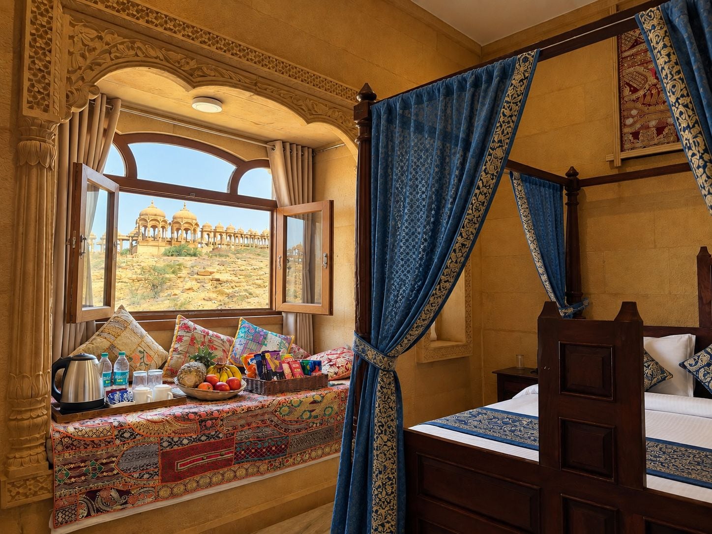 A room with a bed, a window with a view of a desert landscape, a bedside table with a basket of fruits, and a decorative wall.