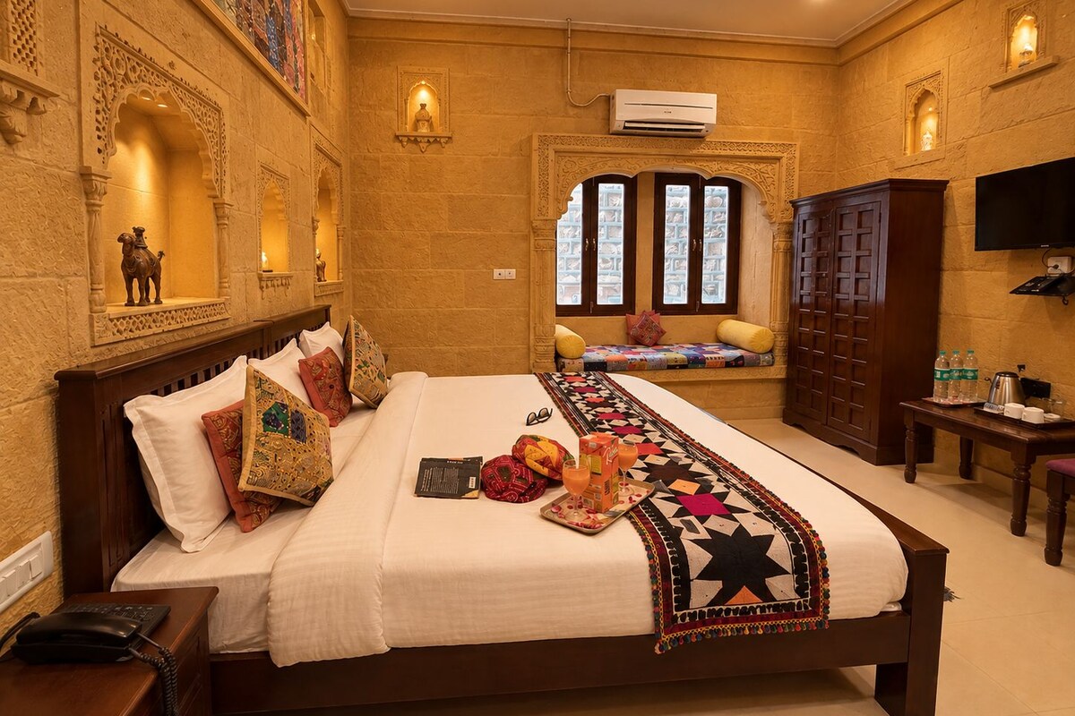 A hotel room with a large bed, a seating area with a view, and a TV on the wall.
