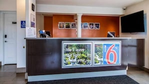 En receptionsdisk med en digital display, en skylt som visar att lokalen är tillgänglig för rullstolsburna och en skylt med siffran ’6’.