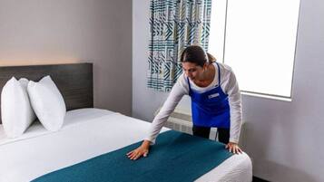 Une chambre d’hôtel avec un lit, des oreillers, une couverture et un rideau à motifs.