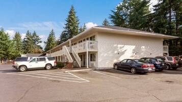 Un motel composé d’un bâtiment à deux étages, d’un espace extérieur abrité et d’un parking où sont stationnés plusieurs véhicules.
