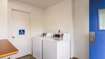 A small laundry area with a washing machine and dryer, a blue door, and a handicap accessible sign.