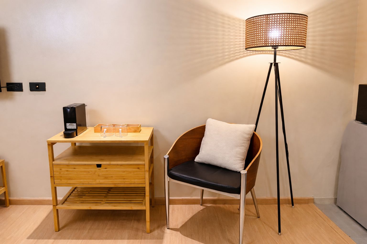Una habitación con un escritorio de madera, una silla, una lámpara de pie y un televisor.