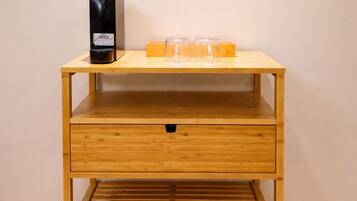 Ein Nachttisch aus Holz mit einer Schublade, ein schwarzes elektronisches Gerät und zwei klare Glasbehälter darauf.