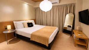 Ein Hotelzimmer mit einem Bett, einem Nachttisch mit Lampe, einem Spiegel und einer Wandklimaanlage.