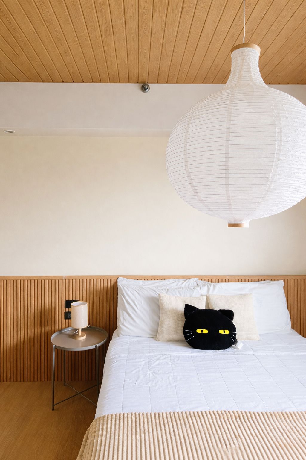 Ein Schlafzimmer mit einem Bett, einem Nachttisch, einer Lampe und einer Pendelleuchte.
