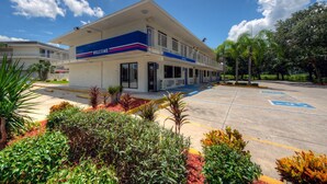 A building with a 'WELCOME' sign, a parking lot with handicapped spaces, and a landscaped area with various plants. - Bright 2-Bed Room, Pool & Free Wifi (Bradenton)