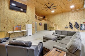 A spacious living area with a large couch, a coffee table, and a flat-screen TV mounted on the wall. - 'Riverside Escape' Ride, Paddle, Relax (Crosby)