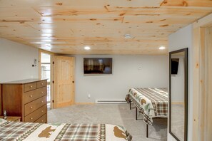 A room with wooden ceiling, a bed with a plaid bedspread, a dresser, and a mirror. - 'Riverside Escape' Ride, Paddle, Relax (Crosby)