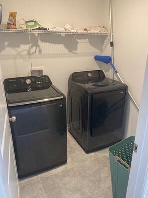A laundry area with two washers and dryers, a mop, and a basket.