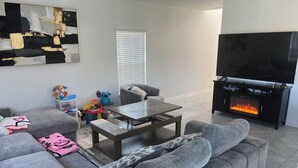 A living room with a grey sofa, a coffee table, a flat-screen TV, and a fireplace. - 10 min from Lego land, the chain of lakes 45 min from Tampa& Disney (Eagle Lake)