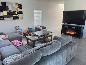 A living room with a grey sofa, a coffee table, a flat-screen TV, and a fireplace. - 10 min from Lego land, the chain of lakes 45 min from Tampa& Disney (Eagle Lake)