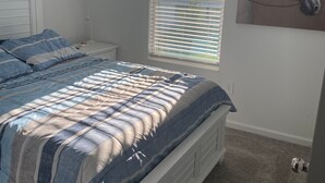 A bedroom with a bed, a window with blinds, a nightstand, and a wall-mounted painting. - 10 min from Lego land, the chain of lakes 45 min from Tampa& Disney (Eagle Lake)