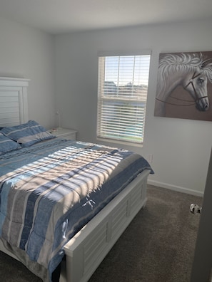 A bedroom with a bed, a window with blinds, a nightstand, and a wall-mounted painting. - 10 min from Lego land, the chain of lakes 45 min from Tampa& Disney (Eagle Lake)