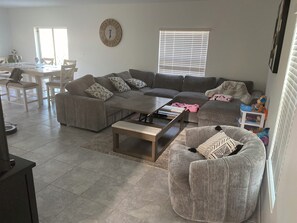 A modern living room with a sectional sofa, a coffee table, and a dining area with chairs and a table.