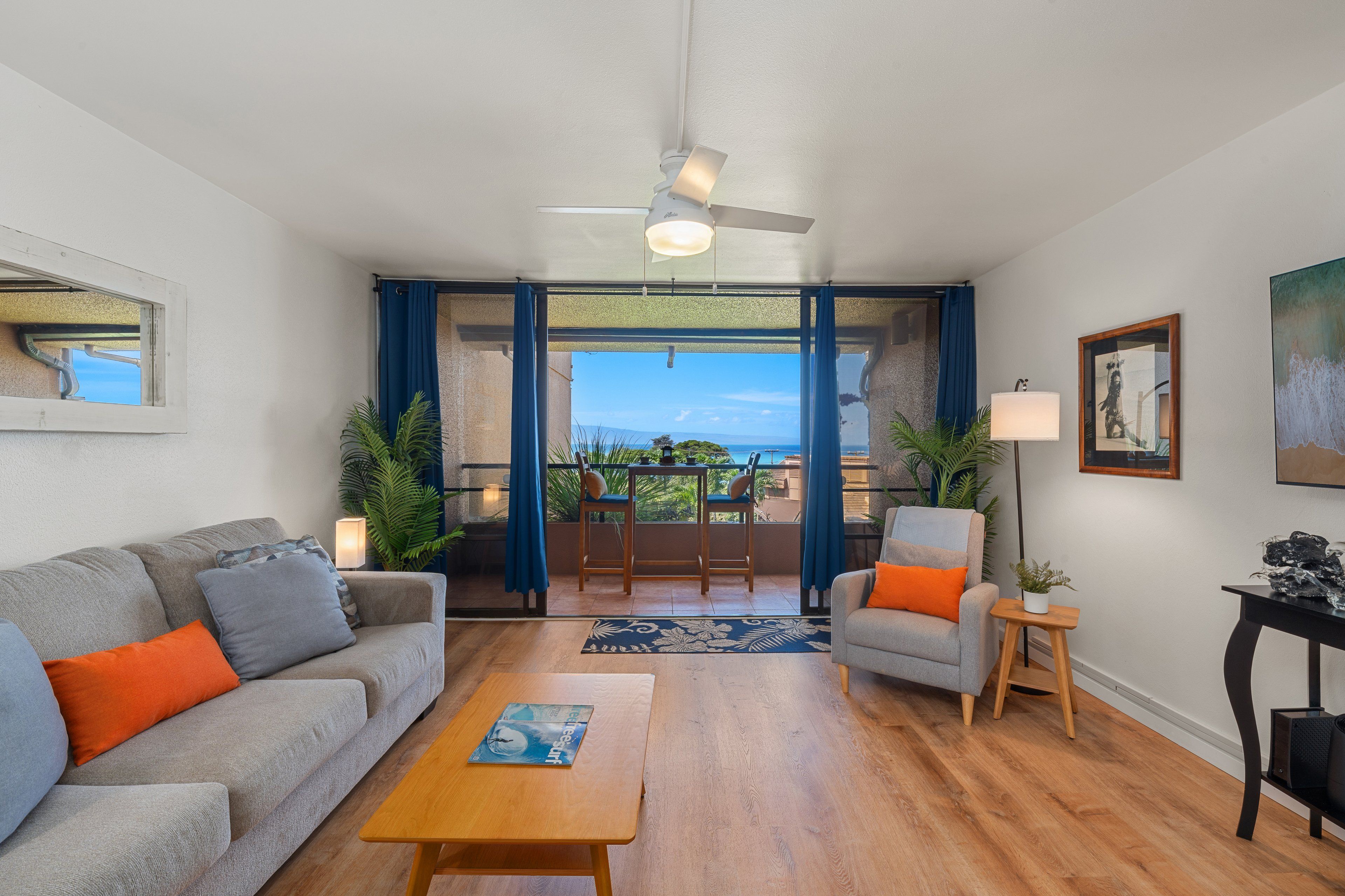 Una sala de estar con sofá, sillón, mesa de centro y vistas al exterior a través de un ventanal.