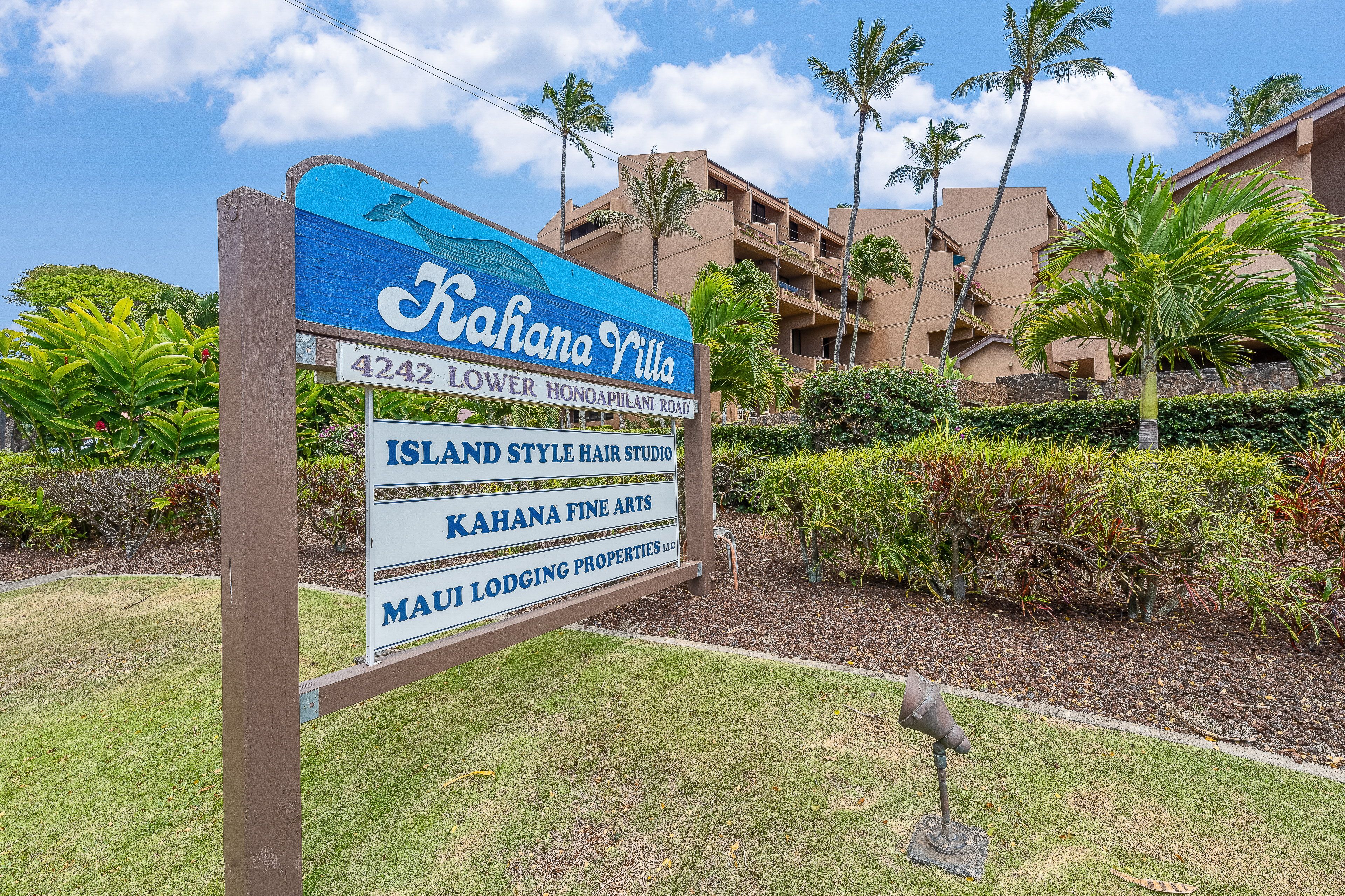 A sign for Kahana Villa with a clear view of the building's architecture and surrounding greenery.