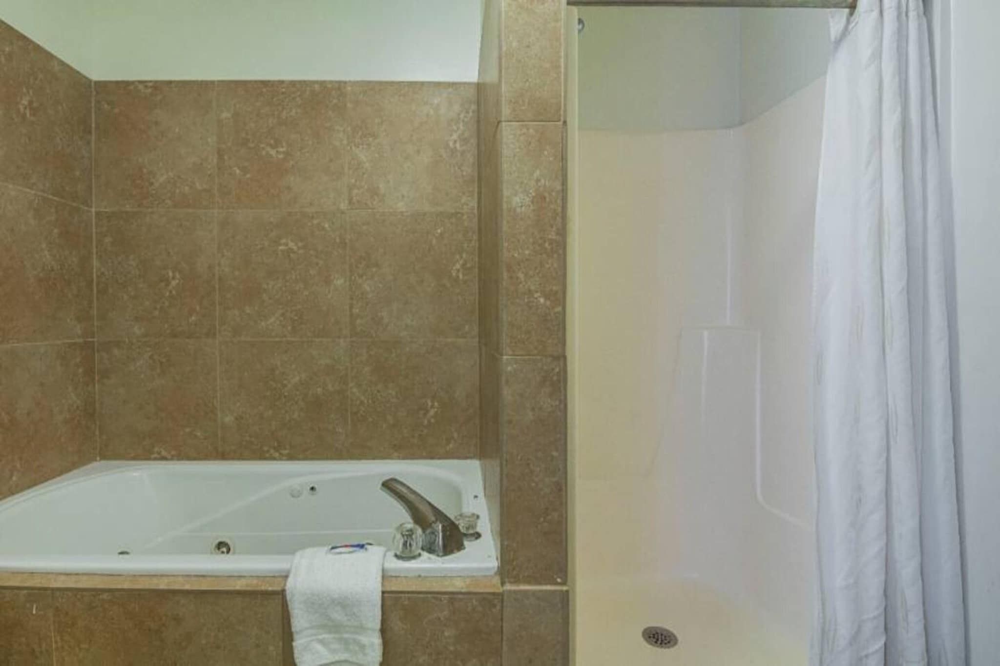 A bathroom with a bathtub, a shower, and tiled walls.